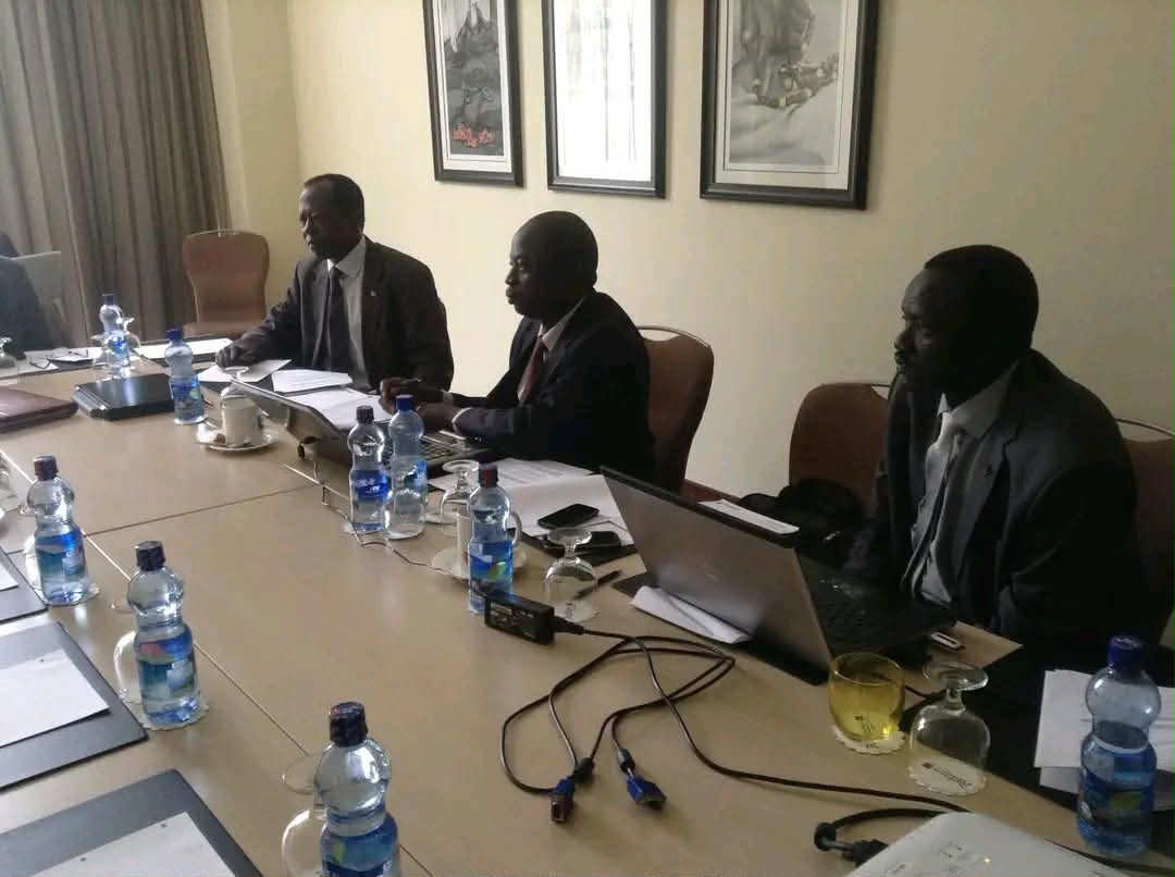 A further view of participants at a meeting table with laptops and papers.